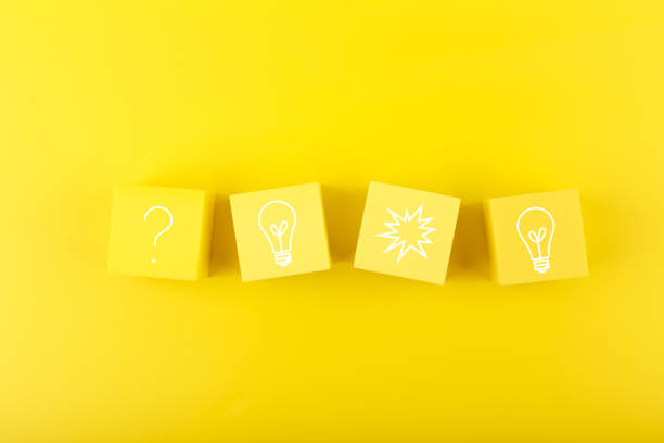 istock Creativity, brainstorming and fresh ideas concept. Light bulb and question signs drawn on toy cubes on yellow background 1355308786