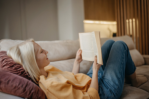 Mid adult woman reading a book while relaxing at home