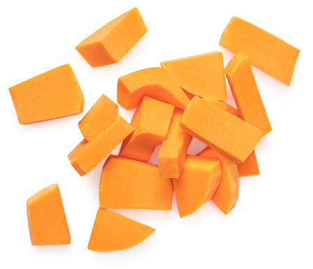 Sliced pumpkin pieces  isolated on white background. Diced Pumpkin cubes. Top view. Flat lay\