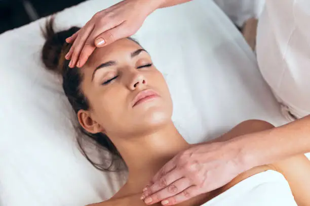 Photo of Beautiful young woman having reiki healing treatment in health spa center