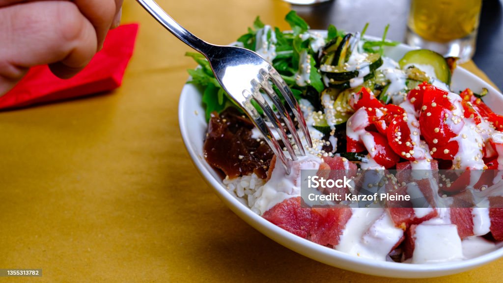 detail of poké plate. Rice, tuna, arugula, vegetables. hand with fork Arugula Stock Photo