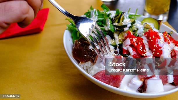 Detail Of Poké Plate Rice Tuna Arugula Vegetables Hand With Fork Stock Photo - Download Image Now