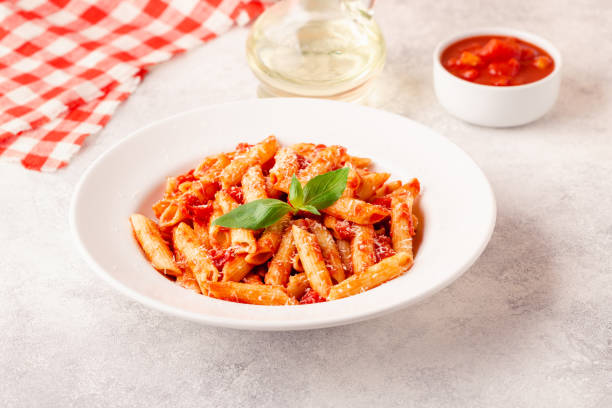 istock Classic italian pasta penne alla arrabiata with fresh basil on a light background, selective focus 1355314062