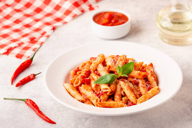 istock Classic italian pasta penne alla arrabiata with fresh basil on a light background, selective focus 1355314063