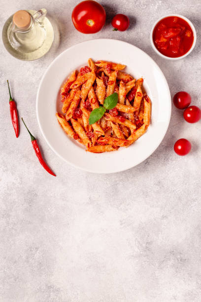istock Classic italian pasta penne alla arrabiata with fresh basil on a light background, top view 1355314350