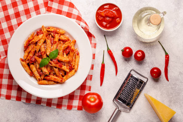 istock Classic italian pasta penne alla arrabiata with fresh basil on a light background, top view 1355314351