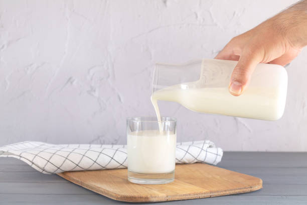 istock Man pouring milk or yogurt from jar into glass 1355315179