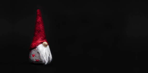Little Santa Claus with red cap isolated against a dark background Little Santa Claus with red cap isolated against a dark background mütze stock pictures, royalty-free photos & images