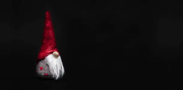 Little Santa Claus with red cap isolated against a dark background