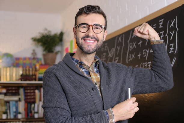 istock Bodybuilder teacher flexing bicep in classroom 1355318003