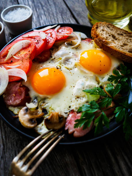 Continental breakfast -  sunny side up eggs, white mushrooms and sausages on wooden table