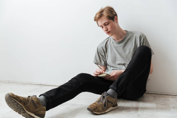 istock Man sitting on the floor and writing something 1355322000