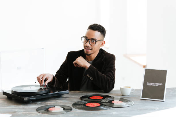 istock African man sitting by the table with record-player 1355328031