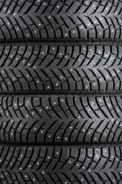 istock New winter car tires with spikes close-up vertically. Texture, background 1355328082