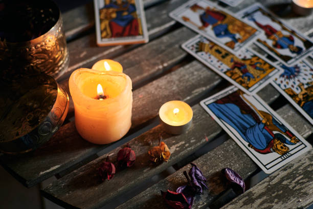 istock Lighted candles on a wooden table filled with tarot cards 1355328345