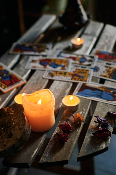 istock Lighted candles on a wooden table filled with tarot cards 1355328350