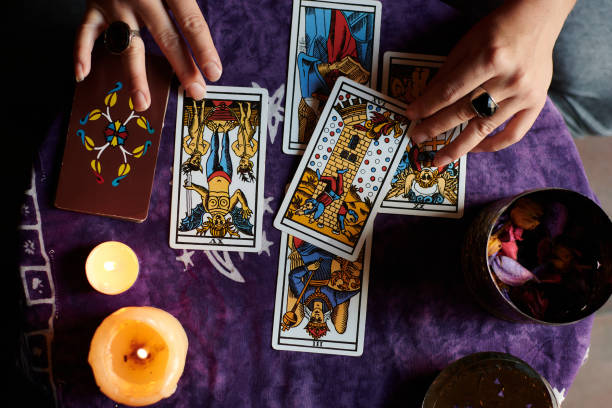 primo piano di un indovino che legge i tarocchi su un tavolo con tovaglia viola - tarot cards foto e immagini stock