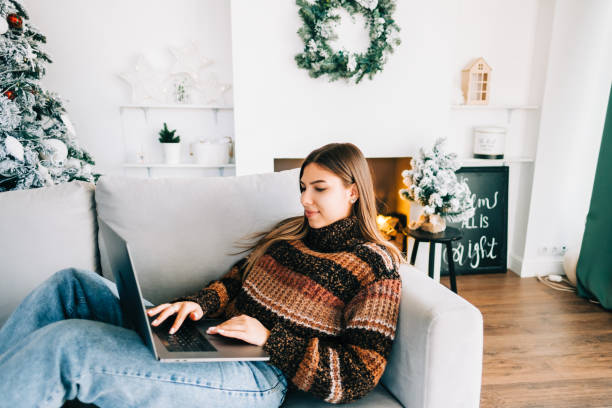 istock Young cheerful caucasian woman using laptop computer in Christmas holidays... 1355328629