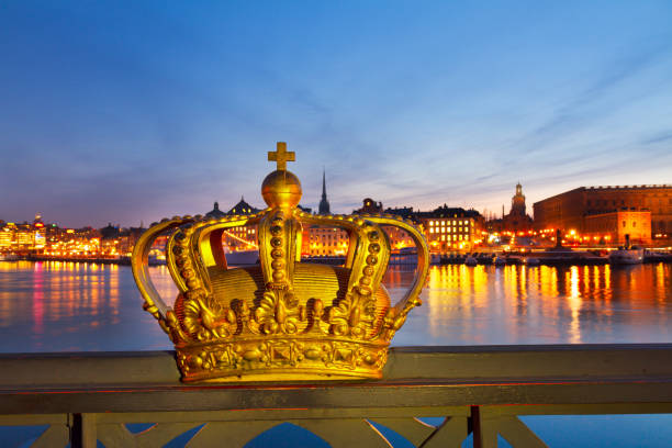 Golden crown ornament on a bridge railing with stockholm cityscape in the background, celebrating swedish royalty and heritage