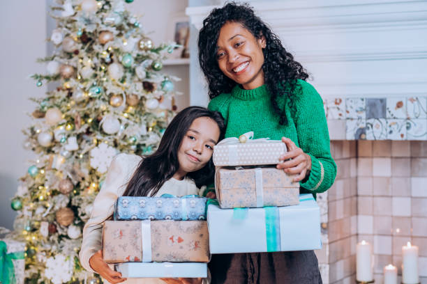 istock Mother and daughter hold Christmas presents hugging 1355332124