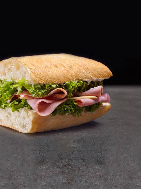 istock Sandwich with ham, cheese and lettuce on dark concrete background 1355333309