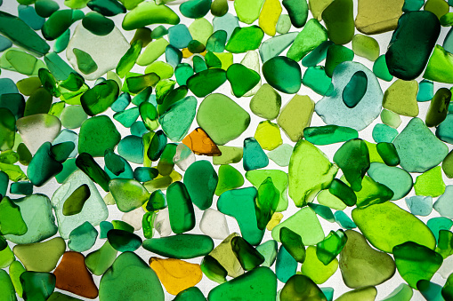 Summer background from sea glass top view. Broken glass from the ocean. Sea pattern. Oceanic mosaic. Natural colors of blue, green, white found on the coast.