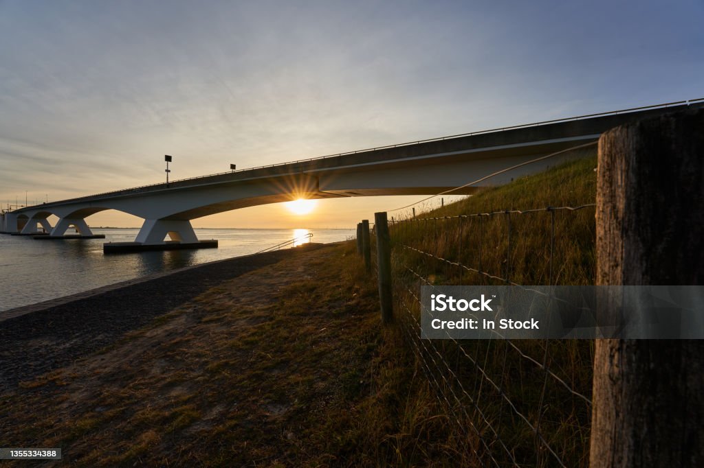 Zeeland bridge in Netherlands. Construction of concrete and steel connects the municipalities of Schouwen-Duiveland and Noord-Beveland.Pasture fence in the foreground, in the evening before sunset. Architecture Stock Photo