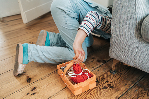 little girl looking for hidden easter gifts under the sofa in living room