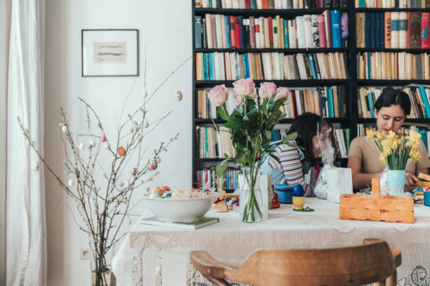view on scene with siblings unwrapping easter gifts from basket at table in living room