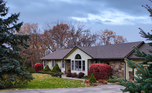 View of Midwestern house   in late  autumn; red bushes in front yard and wilted leaves on the lawn