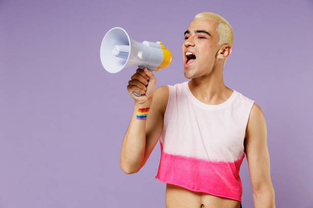 joven gay latino con maquillaje con top rosa brillante sostiene grito en megáfono anuncia venta de descuento date prisa aislado sobre fondo púrpura pastel liso. estilo de vida de la gente moda concepto lgbtq. - gay pride flag audio fotografías e imágenes de stock