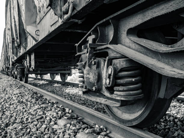 Wheels of a rusty old railroad car on the train tracks Wheels of a rusty old railroad car on the train tracks, the primary suspension, the brake cylinder and swing arm and the car chassis on top. Black and white photography rusty old wagon detail stock pictures, royalty-free photos & images