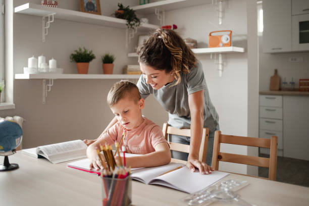 istock Little Boy Completing a School Assignment With His Mother at Home 1355346239