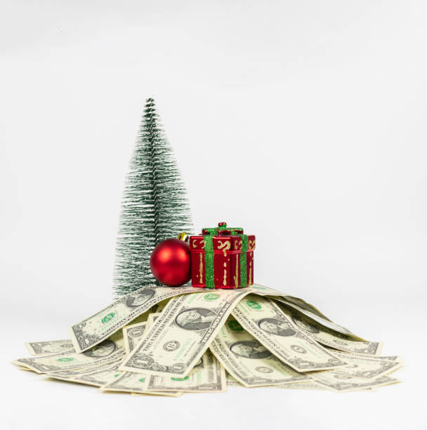 istock Christmas gift standing on a stack of US dollars isolated on white background. Money spent on Christmas 1355348733