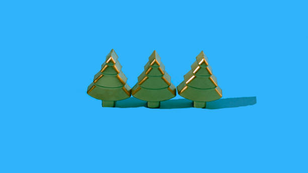 istock Three green and gold Christmas trees in modern geometrical shape on blue background. 1355354167