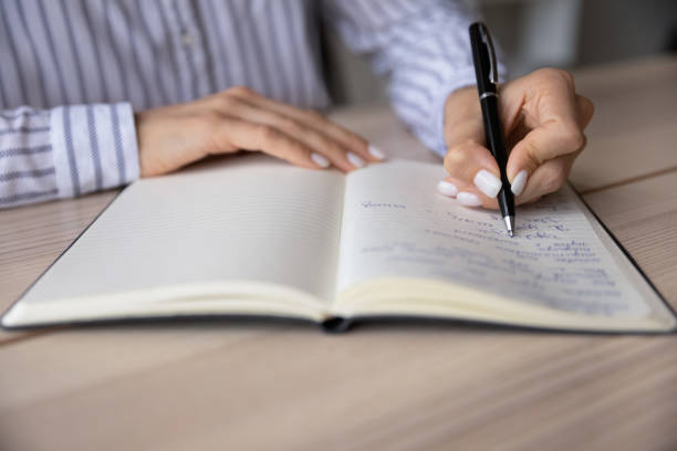 istock Crop close up woman writing in notebook, taking notes 1355358054