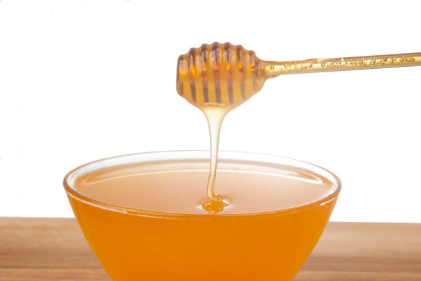istock fresh honey dripping from a spoon into a transparent plate on a white background. organic vitamin health food 1355364493