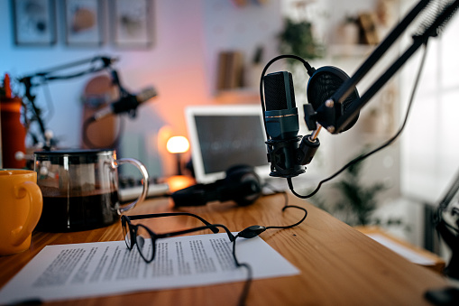 Selective focus of a microphone attached to stand with audio recording equipments with laptop in a studio to record podcast