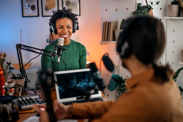 istock Young woman recording podcast on interview with man in studio 1355368040