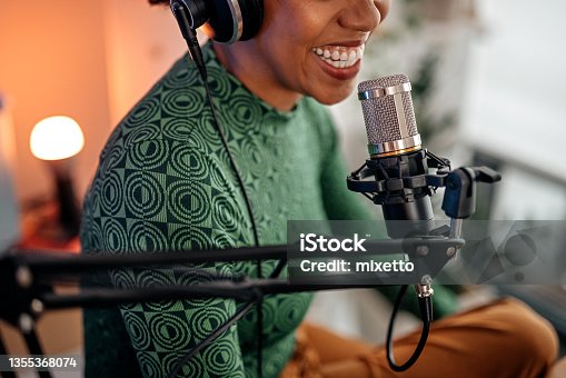 istock Smiling young woman recording podcast 1355368074