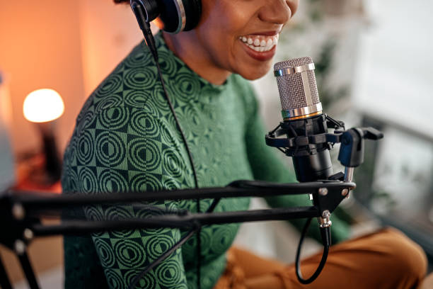 smiling young woman recording podcast - kulaklık seti ses ekipmanı stok fotoğraflar ve resimler