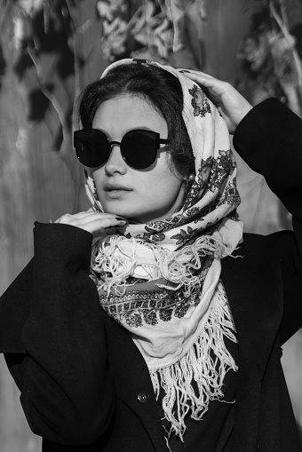 Black and white portrait of a beautiful girl in ethnic headscarf and black sunglasses