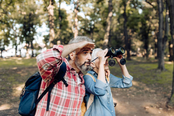istock Mature man and woman exploring the nature with binoculars and having fun 1355372142
