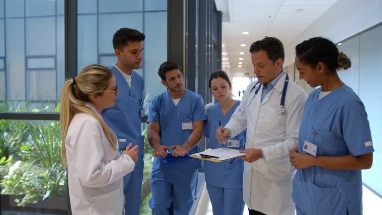 Group of Latin American doctors talking in a meeting at the hospital and listening to the attending while they discuss a patient’s medical chart