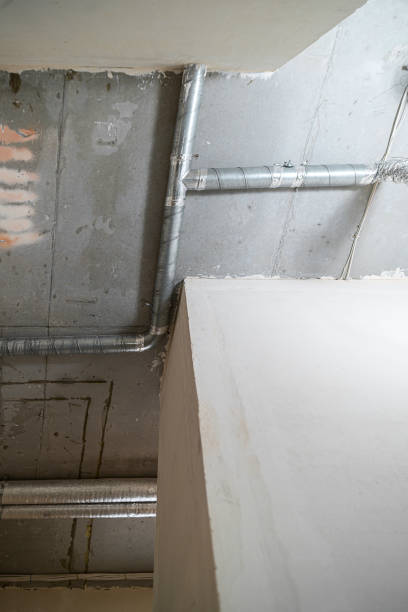 istock Wiring of ventilation pipes on a concrete ceiling in a house under construction. 1355383703