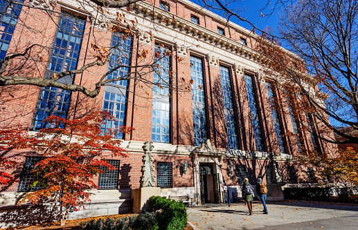 Cambridge, Massachusetts, USA - November 24, 2021: The Harry Elkins Widener Memorial Library (c. 1915). The library houses some 3.5 million books in its stacks and is the center­piece of the Harvard College Libraries.  It honors 1907 Harvard College graduate and book collector Harry Elkins Widener. Two students shown walking up to entrance.