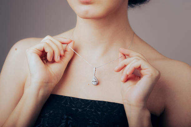 Model Showing Her Beautiful Necklace with Diamond Pendant Elegant woman showing off her beautiful and precious fashion piece of jewelry necklace stock pictures, royalty-free photos & images
