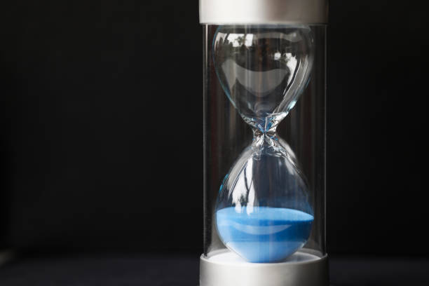istock Stylish glass hourglass with blue sand close up 1355417139