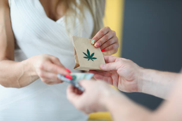 The woman gives money and receives bag marijuana A woman in a white dress gives money and receives a bag of marijuana. Courier delivers the order of pharmacy cannabis cannabis store photos stock pictures, royalty-free photos & images