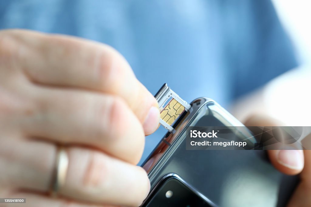 Male hands getting sim card slot of his smartphone out Male hands getting sim card slot of his smartphone out closeup SIM Card Stock Photo